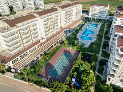 Vue d'un complexe hôtelier avec plusieurs bâtiments, piscine et court de tennis.