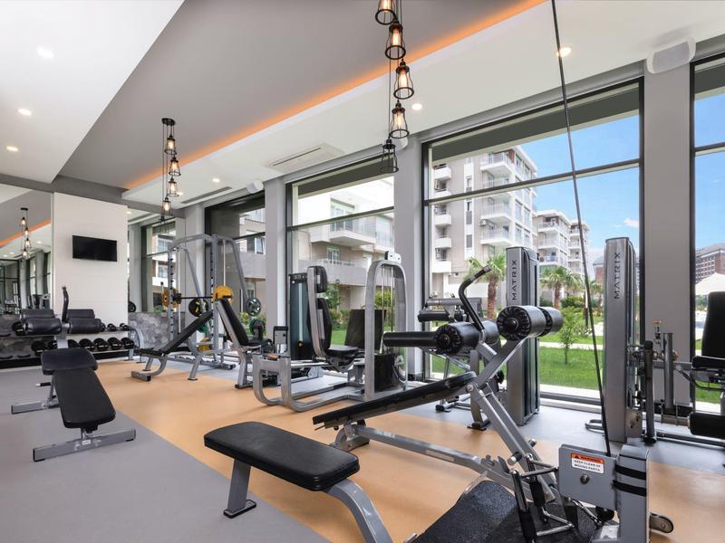 Salle de sport moderne avec grandes fenêtres donnant sur un jardin extérieur.