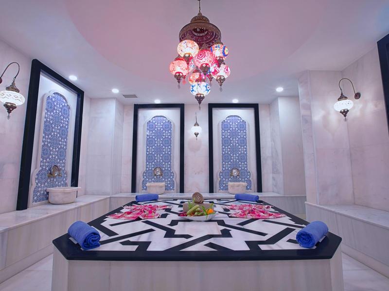 Salon de hammam élégant avec lampes marocaines et serviettes colorées.