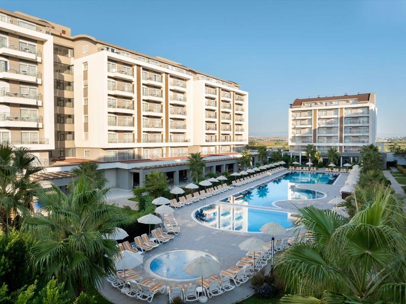 Complexe hôtelier moderne avec deux bâtiments et une grande piscine extérieure sous un ciel dégagé.