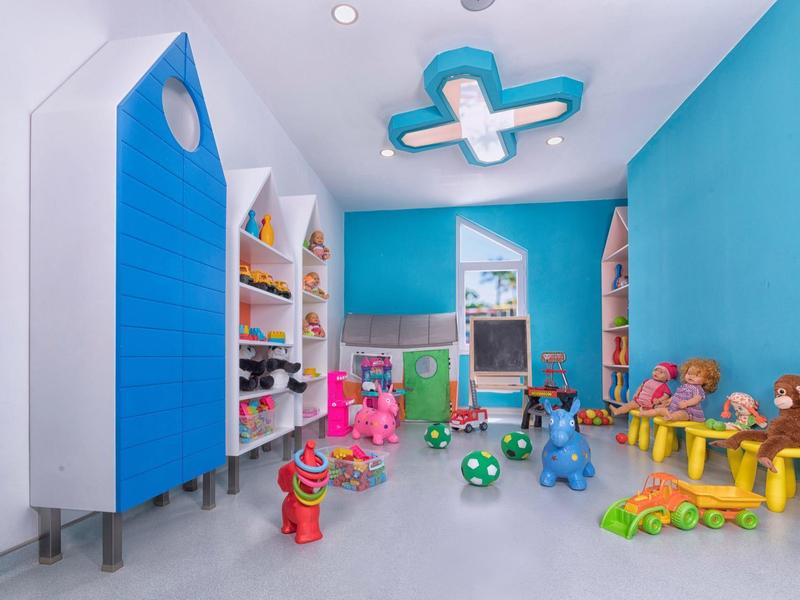 Salle de jeux pour enfants colorée avec jouets et étagères dans une pièce lumineuse.