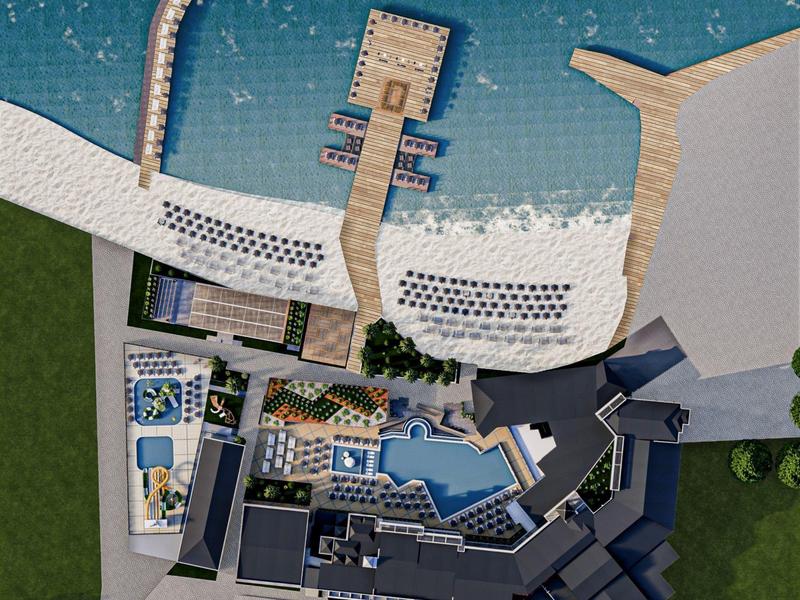 Vista aerea di un resort sulla spiaggia con piscine, moli e spiaggia sabbiosa sul mare.