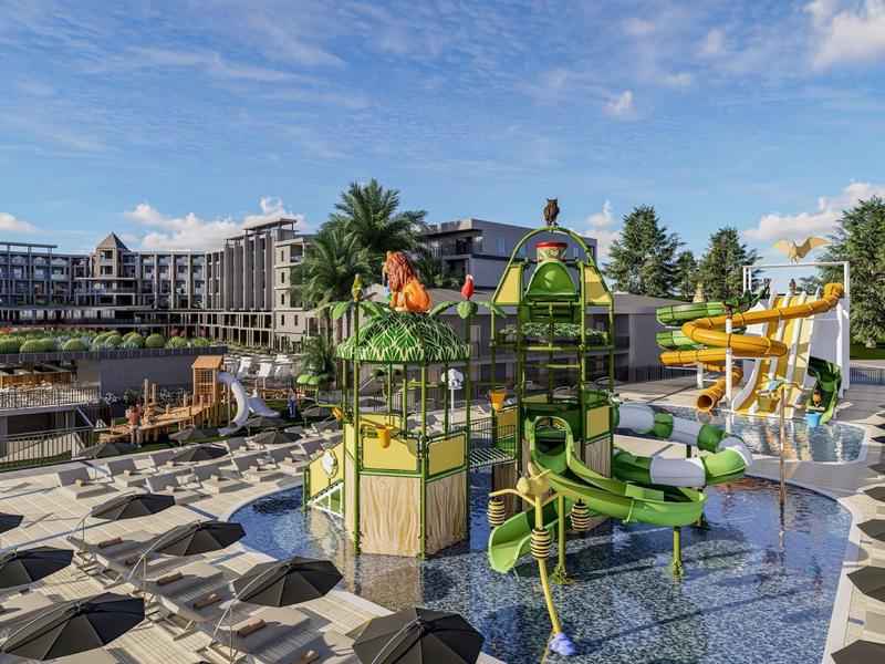 Parco giochi acquatico colorato con scivoli davanti a un edificio alberghiero sotto il cielo azzurro