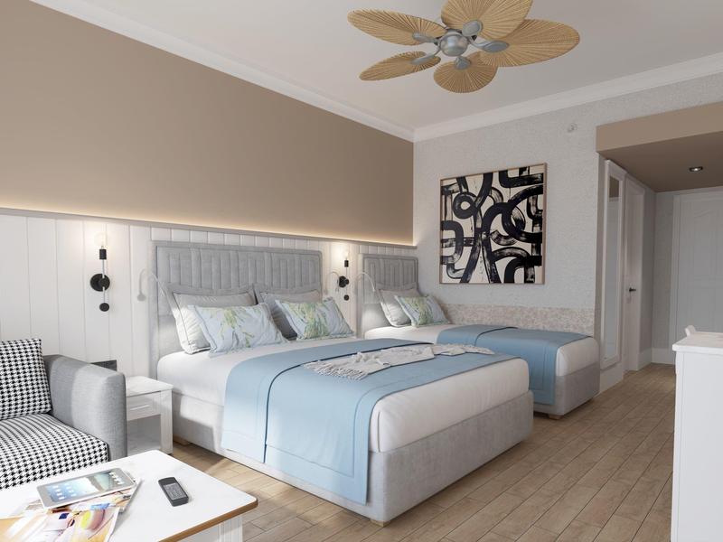 Camera d'hotel luminosa con due letti, ventilatore a soffitto e arredamento moderno.