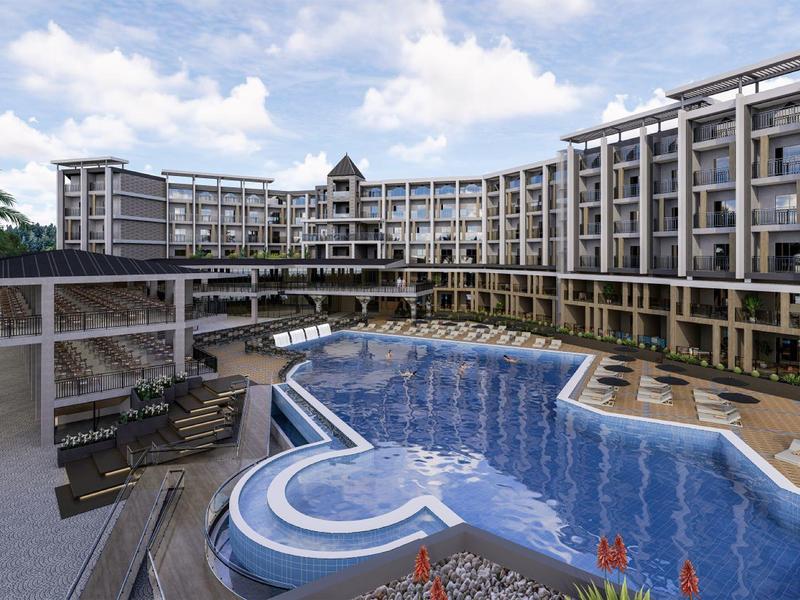 Complesso alberghiero moderno con grande piscina e lettini sotto un cielo azzurro.