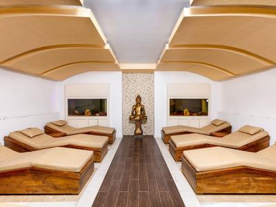 Moderner Ruheraum mit sechs braunen Liegen, weißem Raum und geschwungenen Deckenpaneelen.