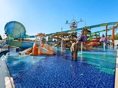 Buntes Außenbecken mit Wasserrutschen und glattem blauen Fliesenboden bei sonnigem Himmel.