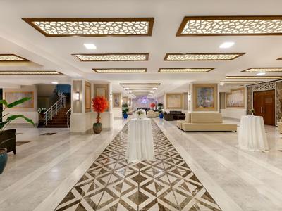 Ampia hall dell'hotel con tavoli eleganti e pavimento in marmo decorativo.