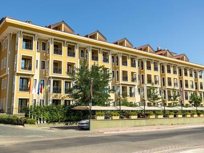 Ein mehrstöckiges gelbes Gebäude mit weißen Fenstern und Dachgauben unter blauem Himmel.