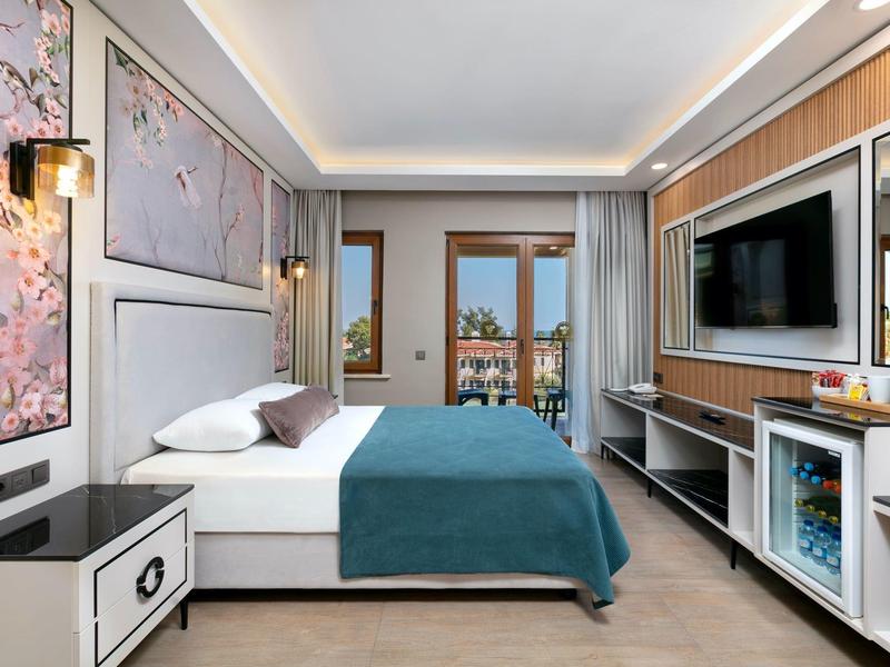 Modernes Schlafzimmer mit großem Bett, blauen Decke, Wandkunst und Balkon mit Blick.