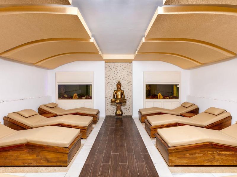 Moderner Ruheraum mit sechs braunen Liegen, weißem Raum und geschwungenen Deckenpaneelen.