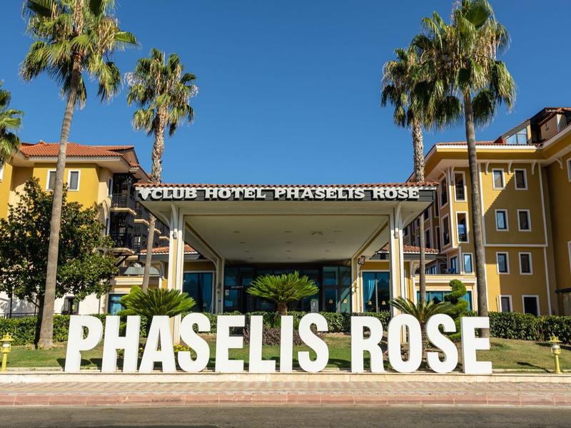 Gelbes Hotelgebäude mit grünen Palmen und großen weißen Buchstaben "PHASELIS ROSE" im Vordergrund.