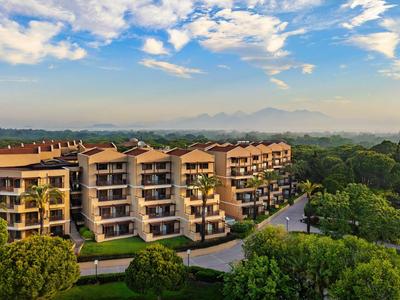 Large multi-story hotel building surrounded by trees under a partly cloudy sky.