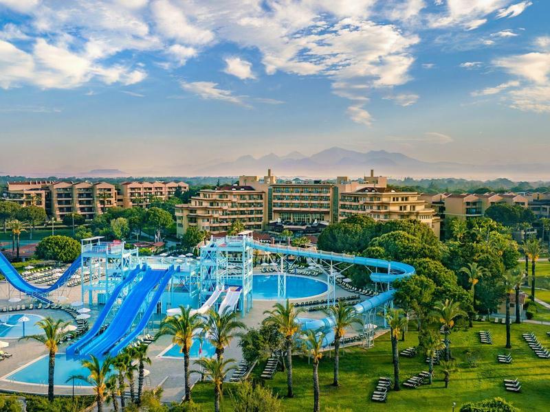 Large resort with multiple pools, water slides, and extensive greenery under a cloudy sky.