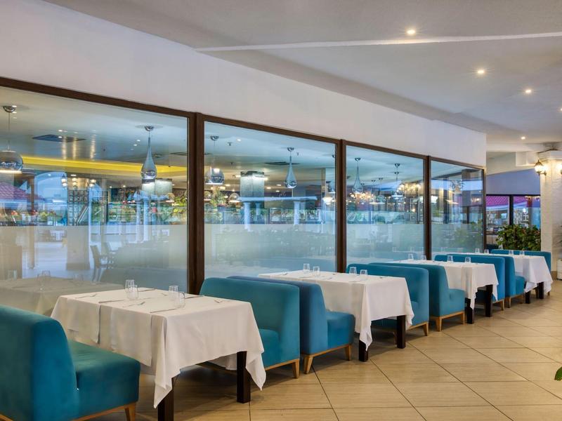 Modern restaurant with blue chairs, white tablecloths, and large windows.