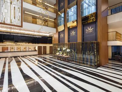 Luksusowy hol hotelowy z czarno-białą podłogą w paski i nowoczesnym oświetleniem.