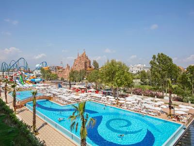 Zewnętrzny basen z leżakami w parku rozrywki pod jasnym niebem.