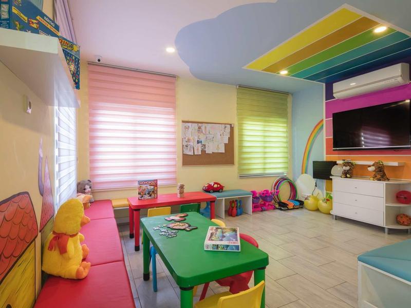 Kolorowy i jasny pokój zabaw z stołami, krzesłami, zabawkami i telewizorem.