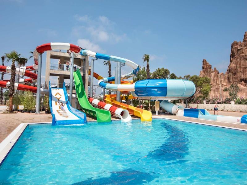 Duży park wodny z kolorowymi zjeżdżalniami i czystym basenem pod niebieskim niebem.