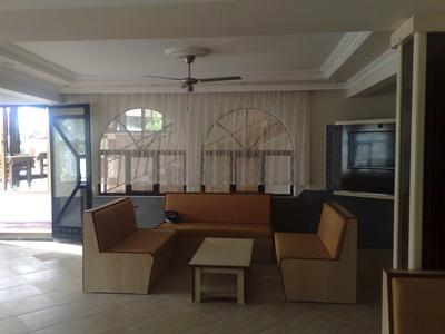 Hotelový pokoj se dřevěnou sedací částí, malým stolem a otevřeným vchodem na terasu.