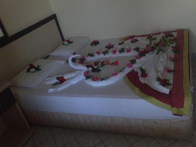 Een hotelbed met witte lakens en handdoeken in zwanenvorm, versierd met rozenblaadjes.