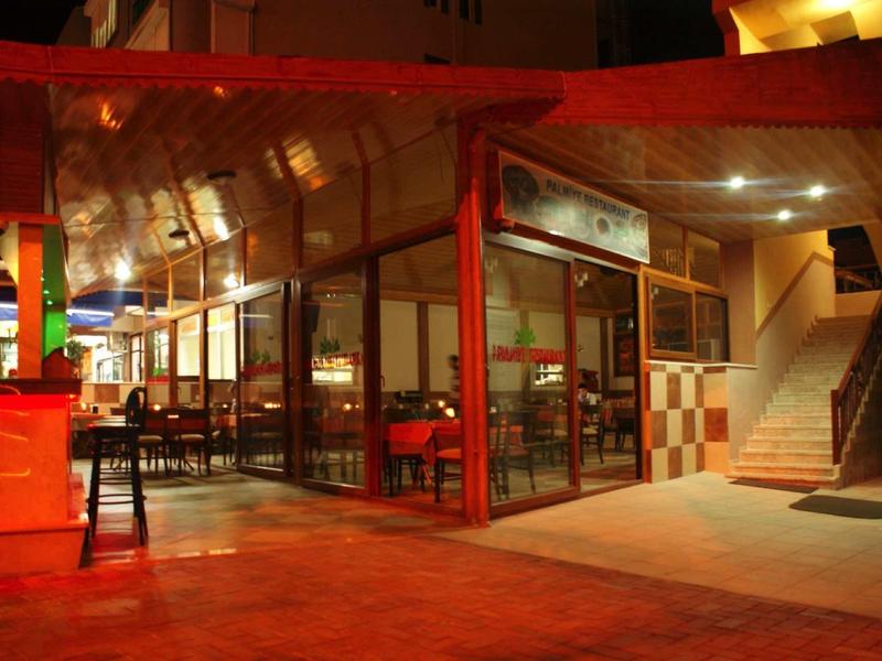 Večerní pohled na exteriér restaurace s červeným krytím a vnitřním osvětlením.