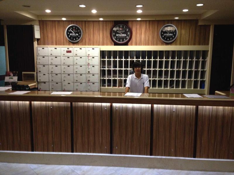 Hotelová recepce s dřevěným pultem a nástěnnými hodinami ukazujícími různé časová pásma