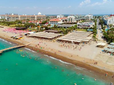 Plage avec hôtels, parasols et eau turquoise claire sous un ciel bleu.