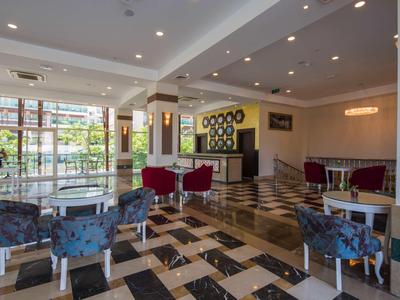 Moderner Hotel-Lobbybereich mit gemustertem Boden, Sesseln in Blau und Rot sowie großen Fenstern.