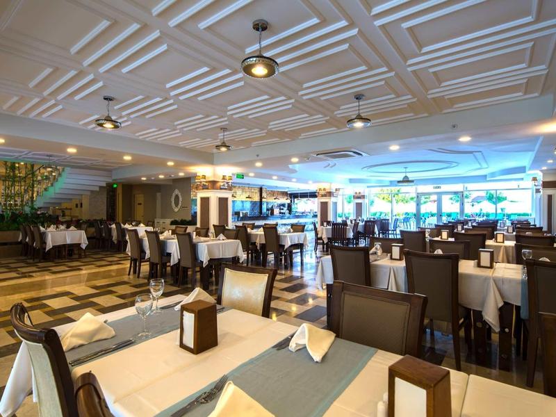 Großer, moderner Speisesaal mit gedeckten Tischen, braunen Stühlen und Tageslicht von Fenstern.