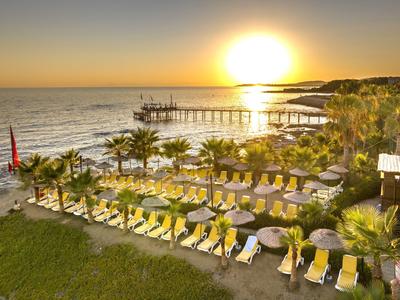 Atardecer sobre el mar con tumbonas y un largo muelle en la playa del hotel.