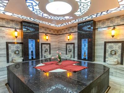 Sala de spa lujosa con fuente central de mármol y adornos decorativos en la pared.