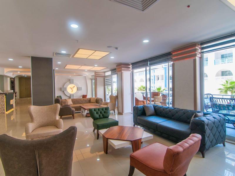 Moderna recepción de hotel con sillones cómodos, sofás y grandes ventanas con vista a una terraza.