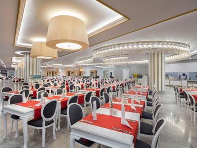 Amplio comedor moderno y luminoso con muchas mesas y sillas, iluminación elegante y diseño sofisticado.