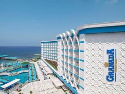 Gran hotel junto al mar con piscina y vista al mar bajo cielo despejado.