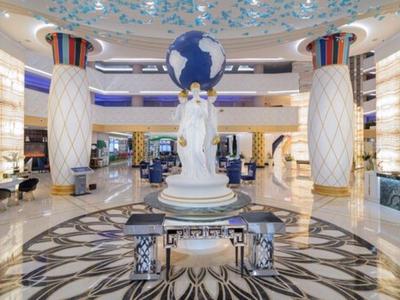 Elegante vestíbulo de hotel con escultura de globo en el centro y suelo de mármol artístico.