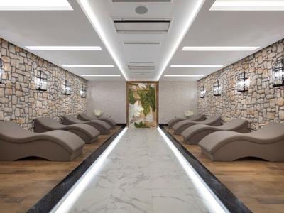 Área de bienestar moderna con paredes de piedra, tumbonas relajantes y iluminación cálida.