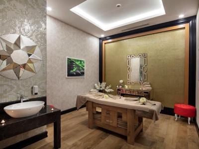 Elegante y acogedora sala de spa con mesa de madera, espejo, lavabo y luz suave.