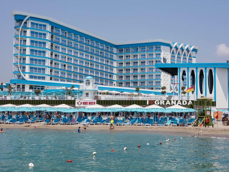 Hotel moderno en la playa con muchos balcones y acentos azules junto al mar.
