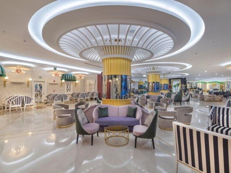 Amplia y elegante zona de salón de hotel con asientos modernos y diseño de iluminación discreto.