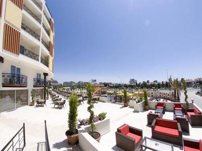 Taras hotelowy z miejscami do siedzenia i widokiem na basen i jasne niebo.