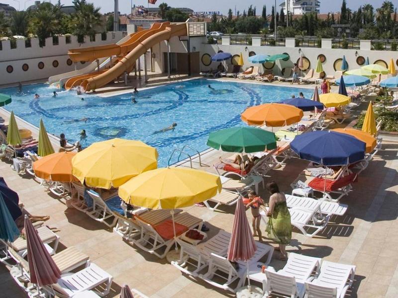 Freizeitbad mit großem Becken, Wasserrutsche und bunten Sonnenschirmen, viele Liegestühle.