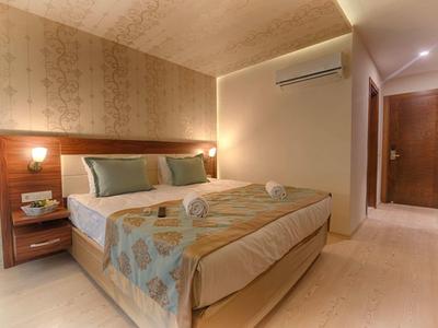 Modern hotel room with double bed, bedside tables, and soft lighting.