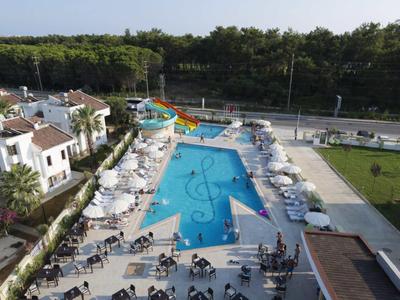 Large outdoor pool with water slide, sun loungers, and surrounding buildings in daylight