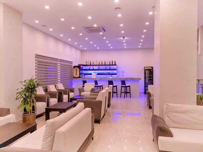 Elegant hotel lounge area with white sofas, tables, and stylish bar in the background.