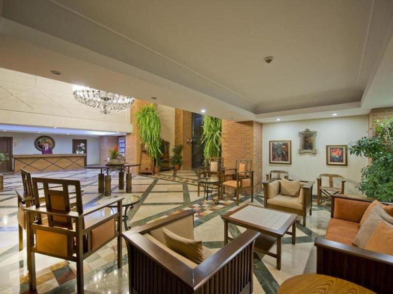 Innenraum einer Hotellobby mit Sitzbereichen, Pflanzen und warmem Licht.