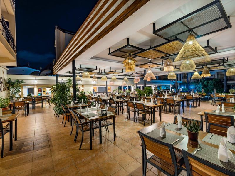 Offener Hotelrestaurantbereich mit gedeckten Tischen und moderner Beleuchtung bei Nacht.