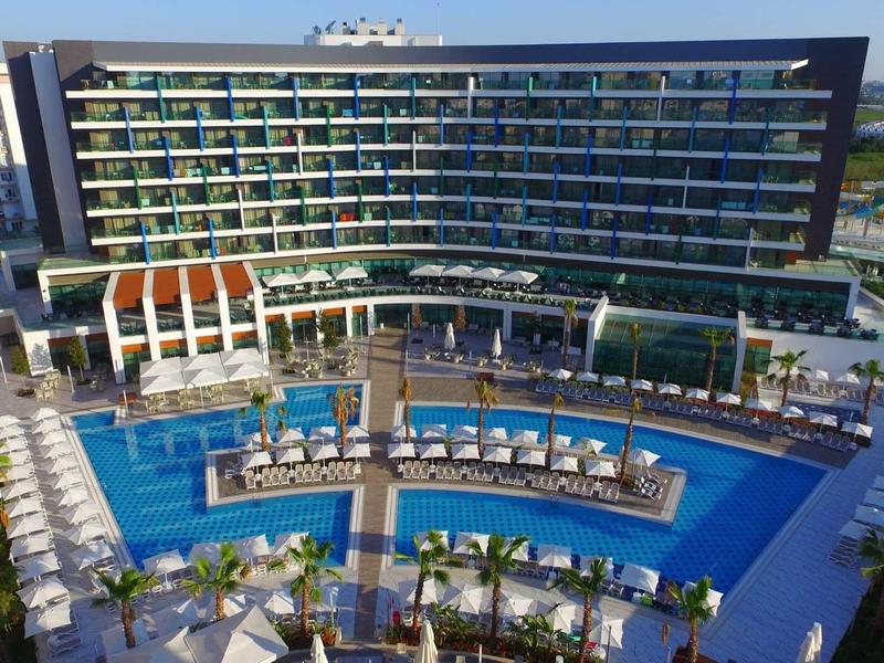 Modern hotel met groot zwembad en ligbedden in tropische omgeving.