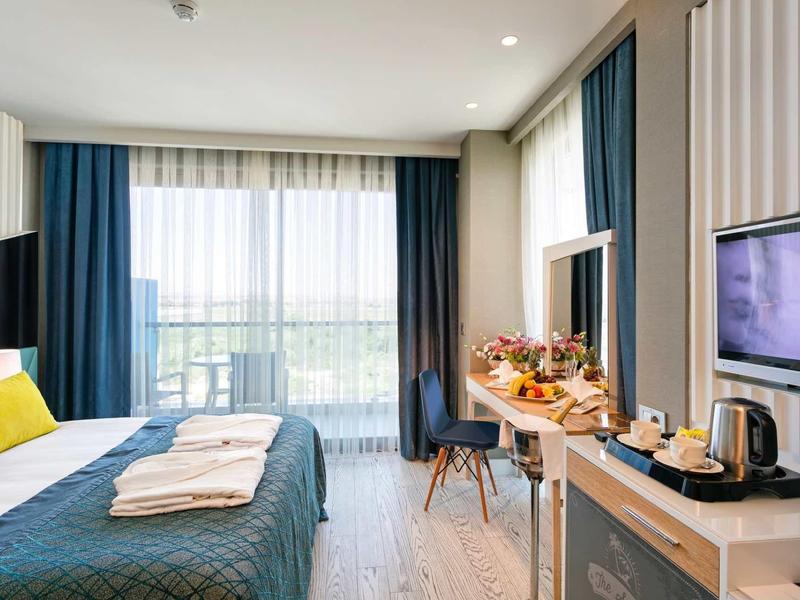 Modern hotelkamer met tweepersoonsbed, bureau en balkonzicht.