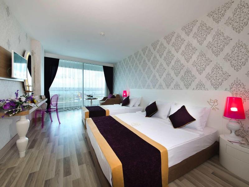 Modernes Schlafzimmer mit Doppelbett, gemusterten Wänden, Glasfenster und violetten Akzenten.